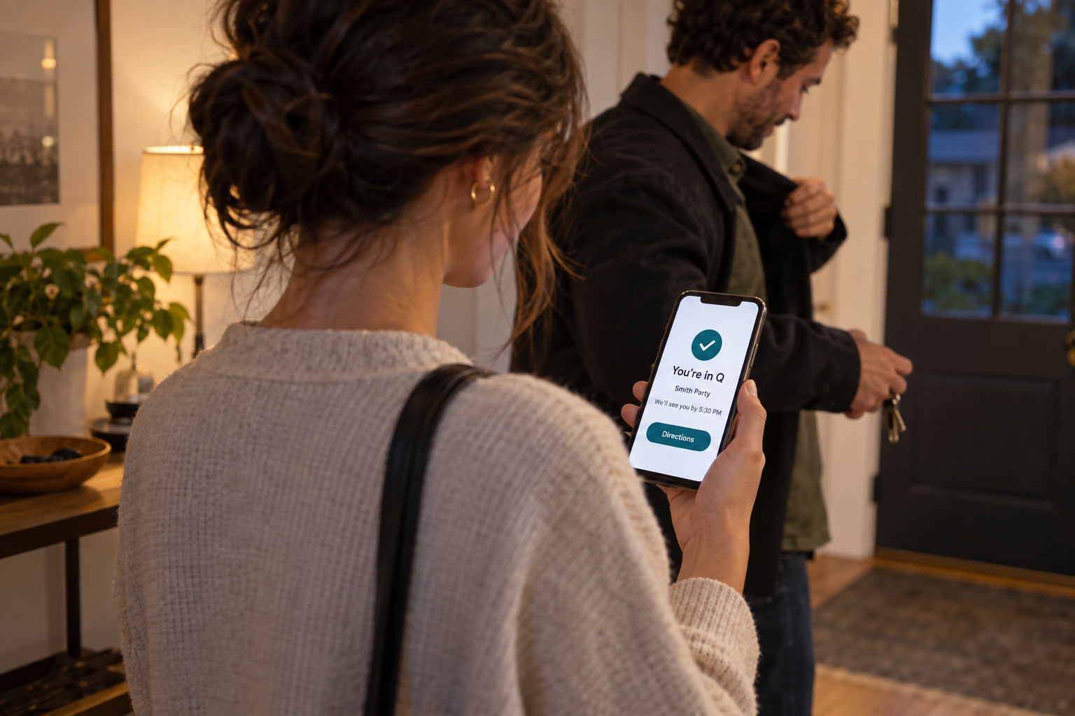 Couple checking their phone showing a Q waitlist confirmation before heading out